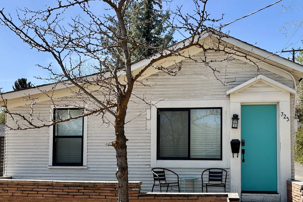 The front porch with a turquoise door, bare tree, and porch seating. The scene captures the charm of stepping out onto the porch to enjoy morning coffee or chat with neighbors, with a clear view of the neighborhood surroundings.